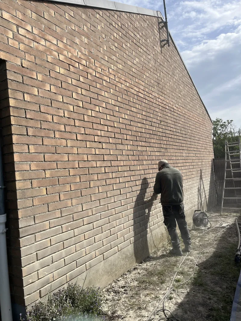 Artisan au travail le long d'une façade en briques