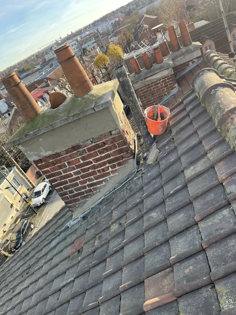 Souche de cheminée en briques reprise au mortier, sur une toiture en tuiles